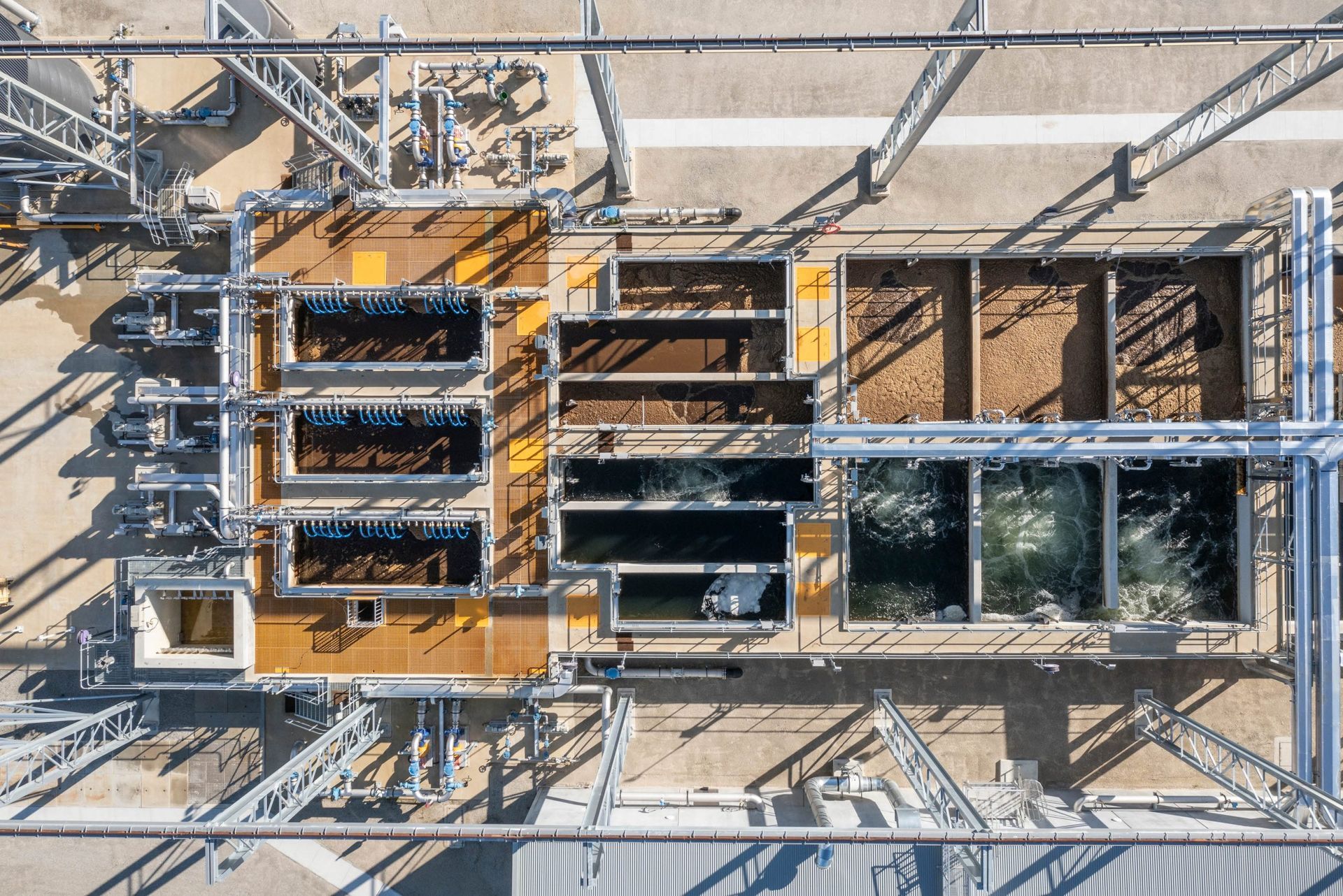 Overhead view of an industrial water treatment plant with tanks, piping, and structural supports.