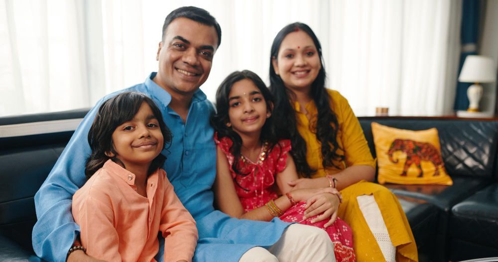 A family is sitting on a couch in a living room.