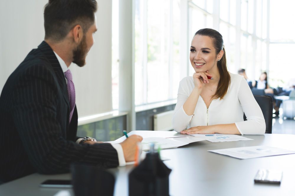 A man and a woman are sitting at a table having a job interview.