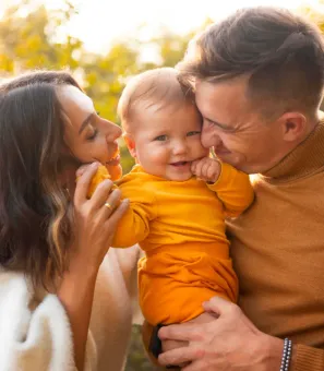 A man and a woman are holding a baby in their arms.