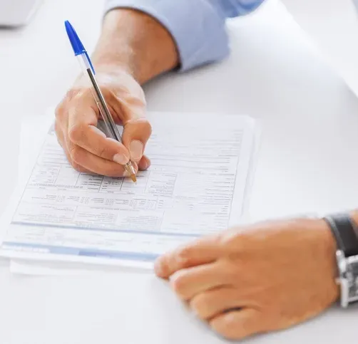 A person is writing on a piece of paper with a pen