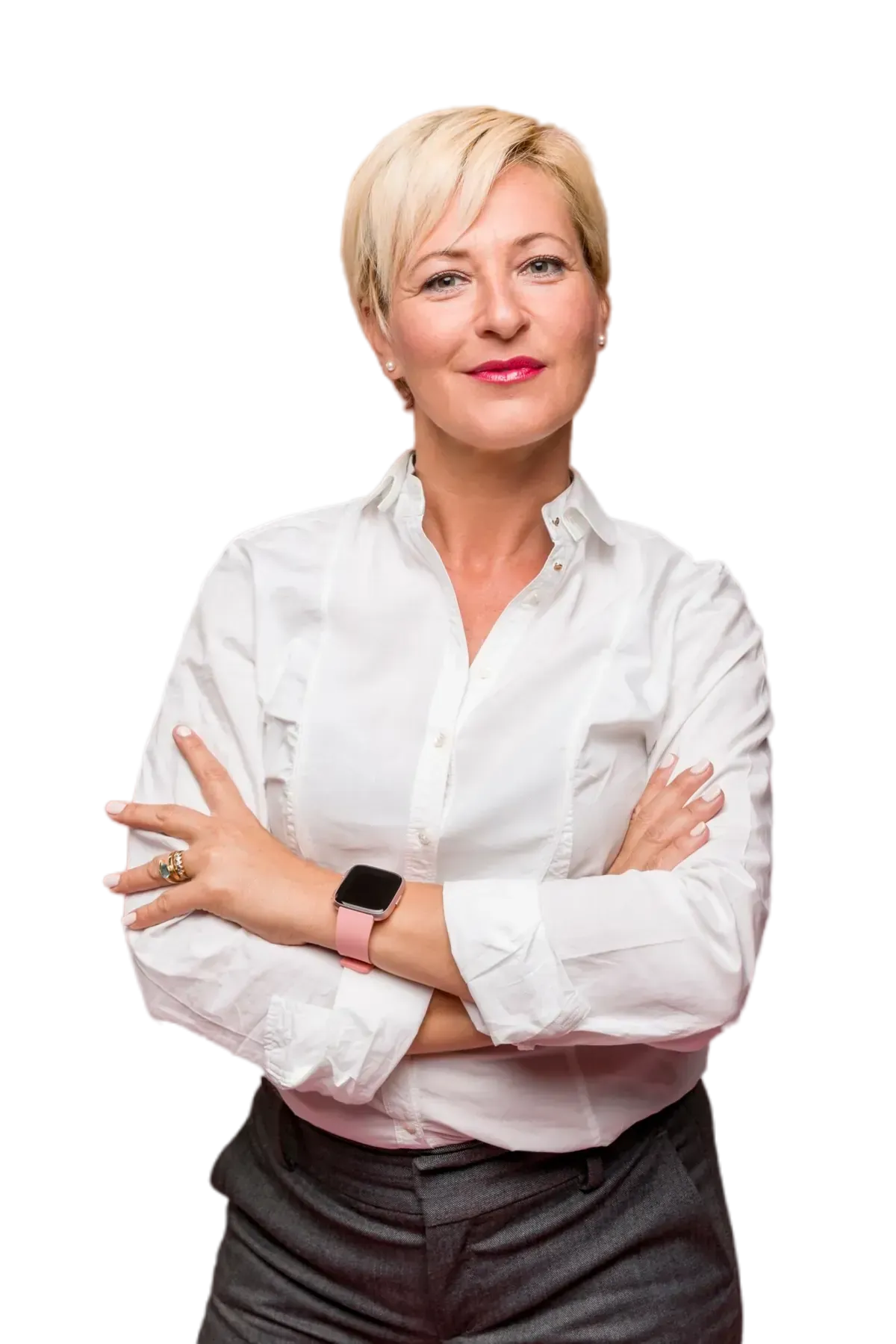 A woman in a white shirt and gray pants is standing with her arms crossed.