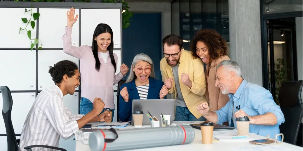 A group of people are sitting around a table in front of a laptop computer.