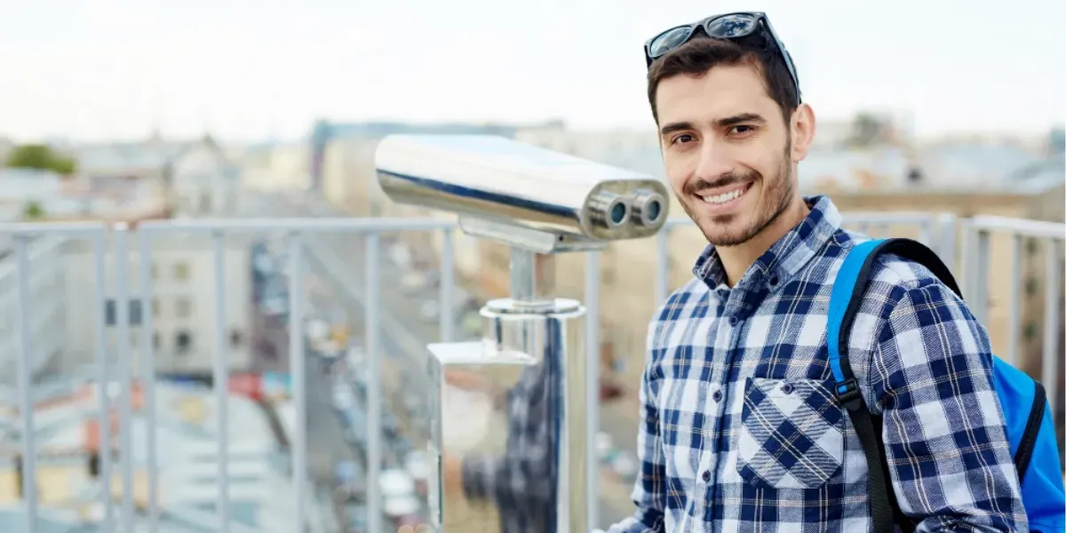 A man with a backpack is standing in front of a camera.