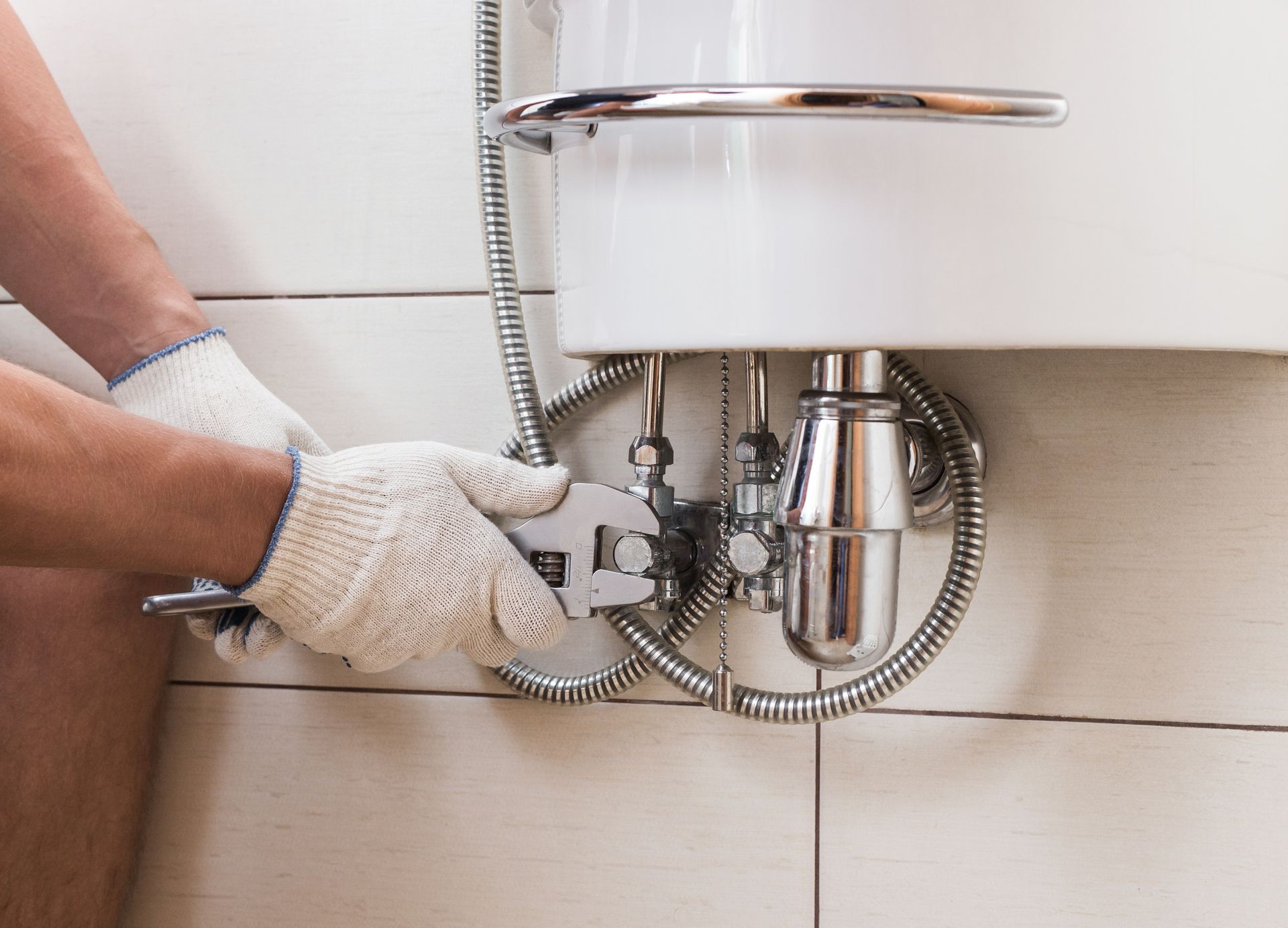 A man is fixing a sink with a wrench.