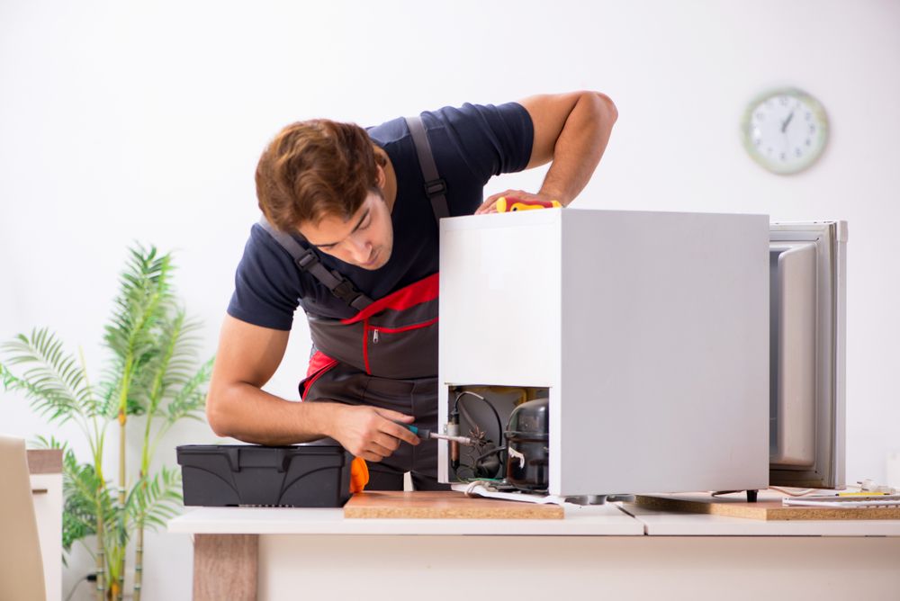 Man Repairing A Refrigerator. He Uses A Screwdriver. Indoors — Ace Fridge Door Seals in Cooktown, QLD