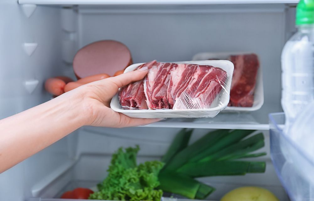 Hand Placing A Tray Of Raw Meat Into A Refrigerator With Eggs — Ace Fridge Door Seals in Smithfield, QLD