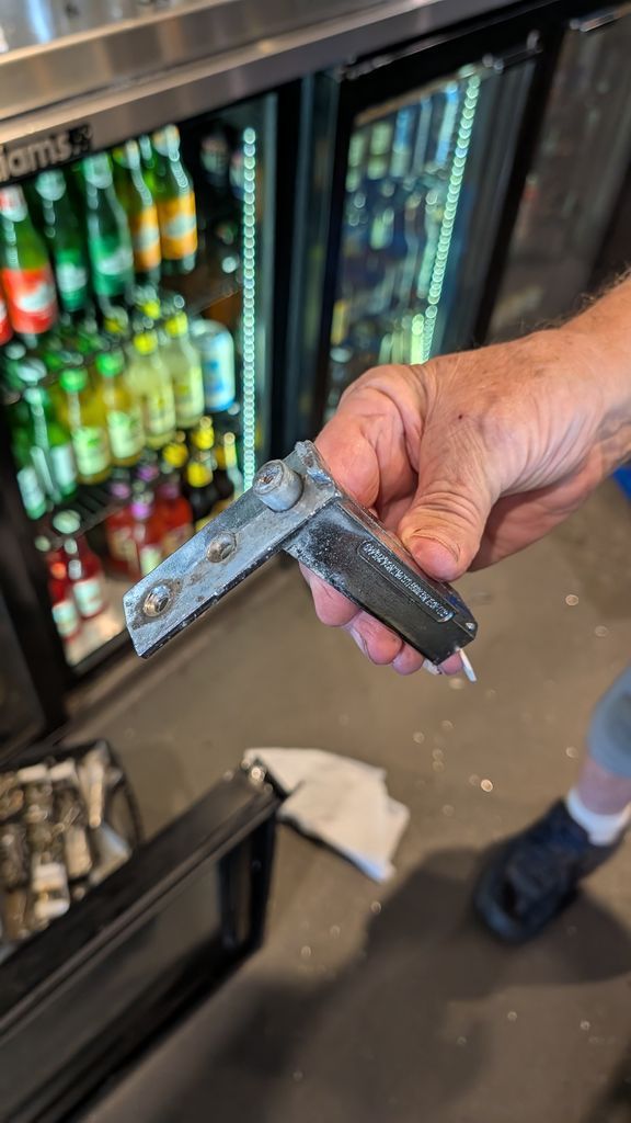 Hand Holding a Door Seal in Front of a Refrigerated Drink Cooler in a Store — Ace Fridge Door Seals In Cairns, QLD