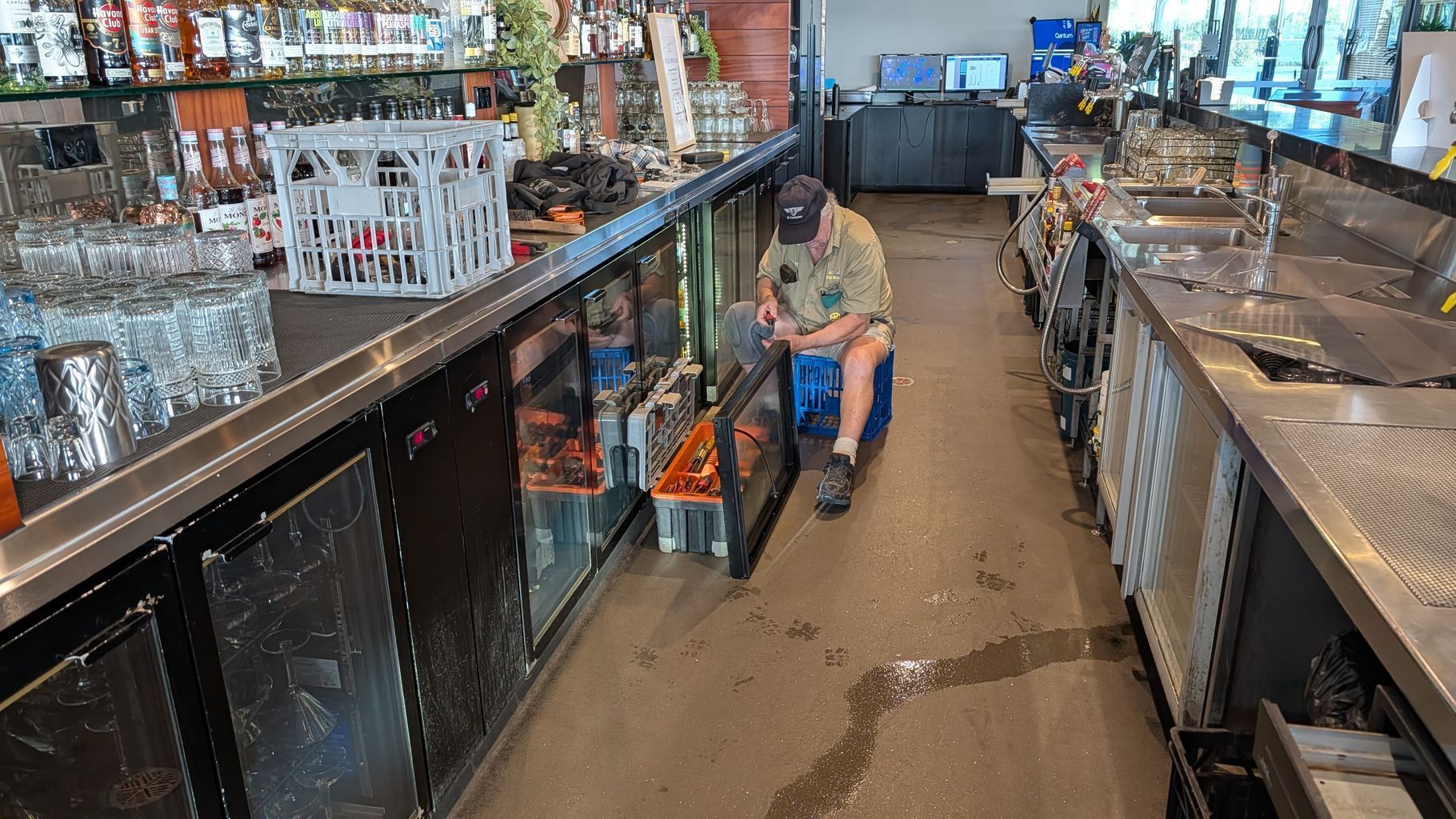Person Kneels in a Narrow Bar, Cleaning the Floor — Ace Fridge Door Seals In Cairns, QLD