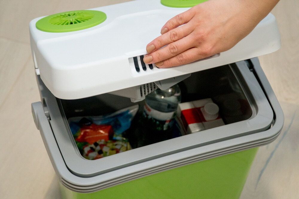 A Person Is Opening A Green And White Cooler Filled With Food And Drinks — Ace Fridge Door Seals In Cairns, QLD