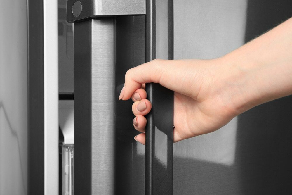 A Person Is Opening A Refrigerator Door With Their Hand — Ace Fridge Door Seals In Cairns, QLD