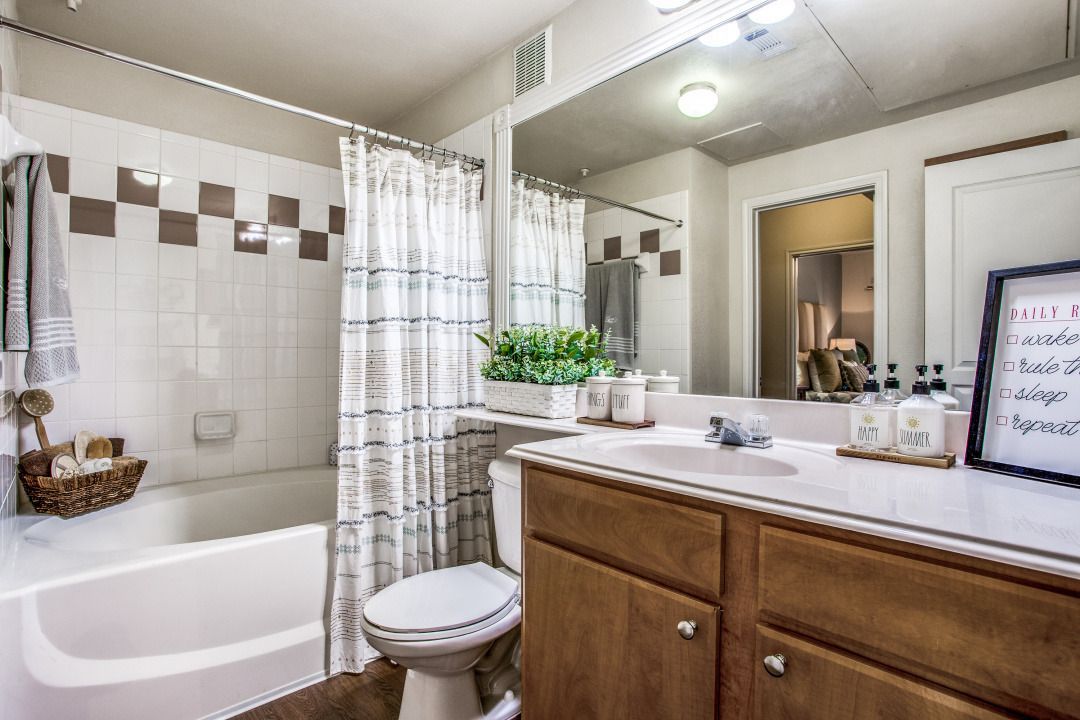 Bathroom with a shower/tub combo, toilet, and wood vanity.