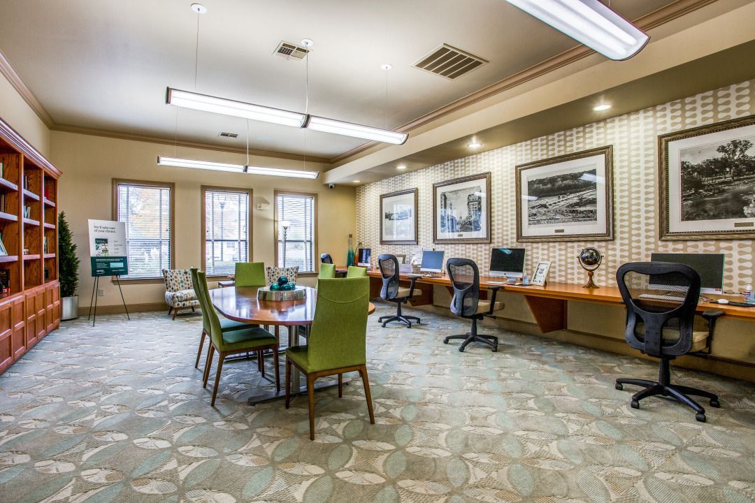 Community lounge with a long desk, computers, and seating under warm lighting.