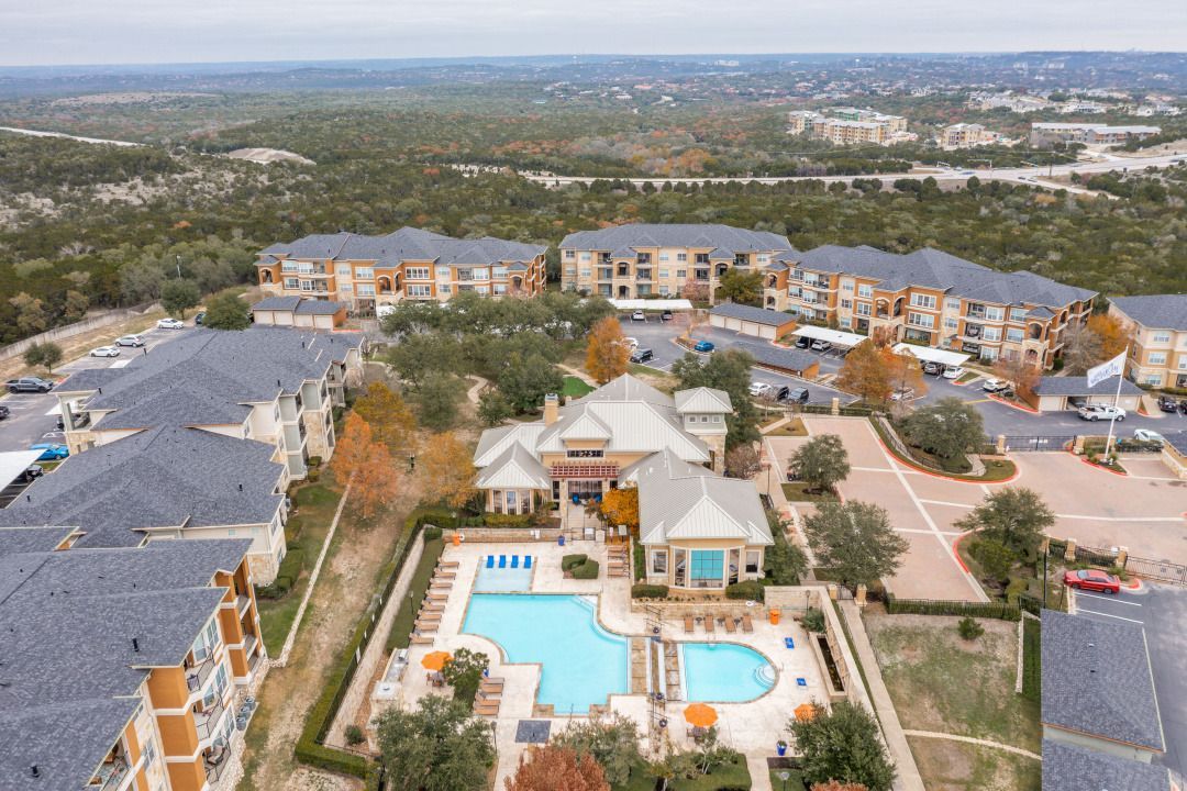 Aerial view of a multi-building apartment complex with a central pool and courtyards.