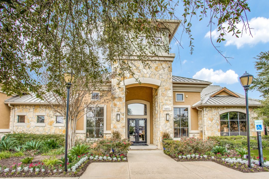 Front entrance of apartment community featuring stone facade and landscaping.