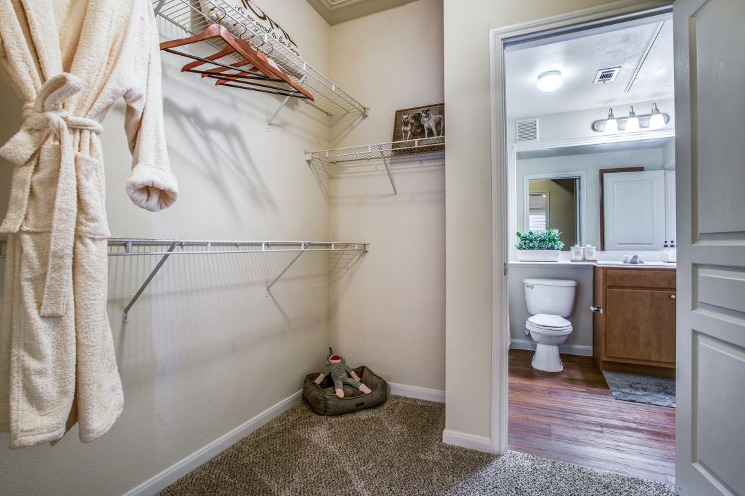 Walk-in closet with wire shelves, a robe, and a doorway to an adjacent bathroom.