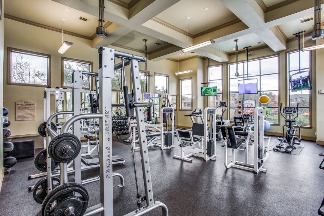 Interior of a modern community gym with weight machines, cardio equipment, and free weights.