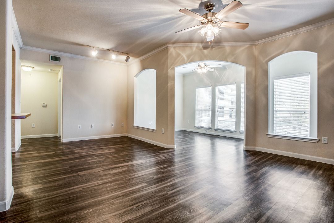 Living room with dark wood flooring, arched window alcoves, and ceiling fans.