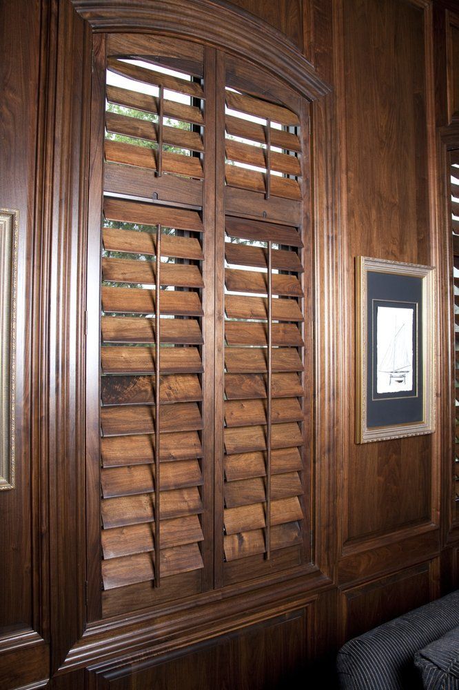 A wooden window with shutters on it in a living room.