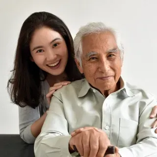 An elderly man and a young woman are posing for a picture.