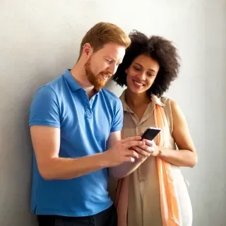 A man and a woman are looking at a cell phone together.