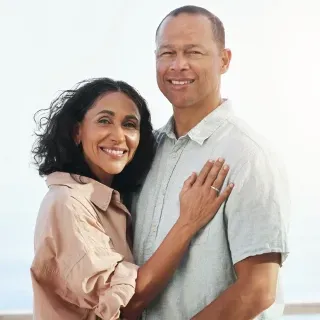 A man and a woman are posing for a picture and the woman is hugging the man.