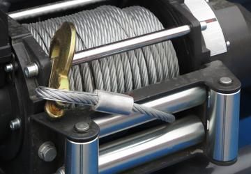 Close-up of a winch with a steel cable wrapped around the drum and a hook attached.