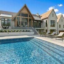 Large house with a pool in front, bright blue sky.