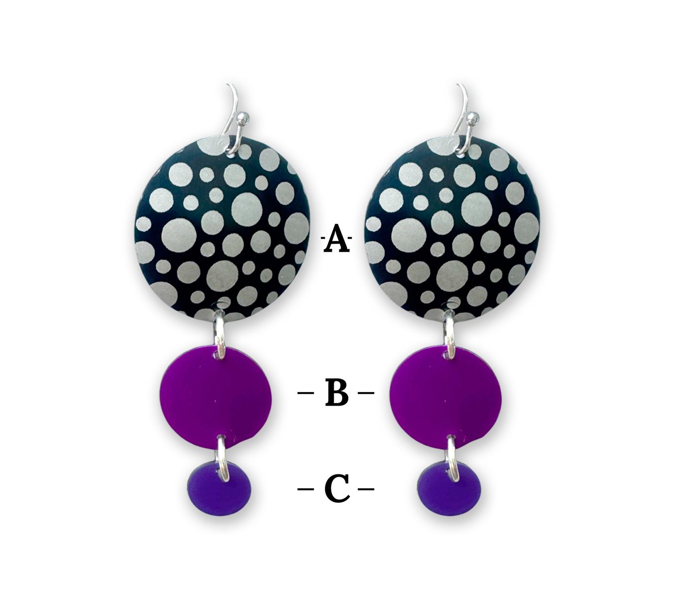 Woman wearing layered circle earrings; black and white polka dot top, purple middle, and small purple bottom with a silver necklace.
