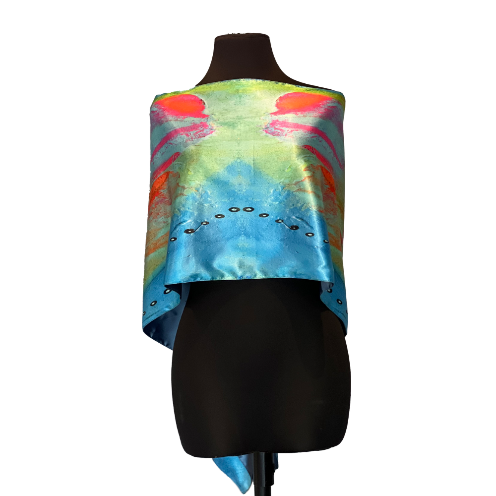 Silk scarf on a black mannequin. Scarf has colorful abstract design: blue, green, orange, and black circular shapes.