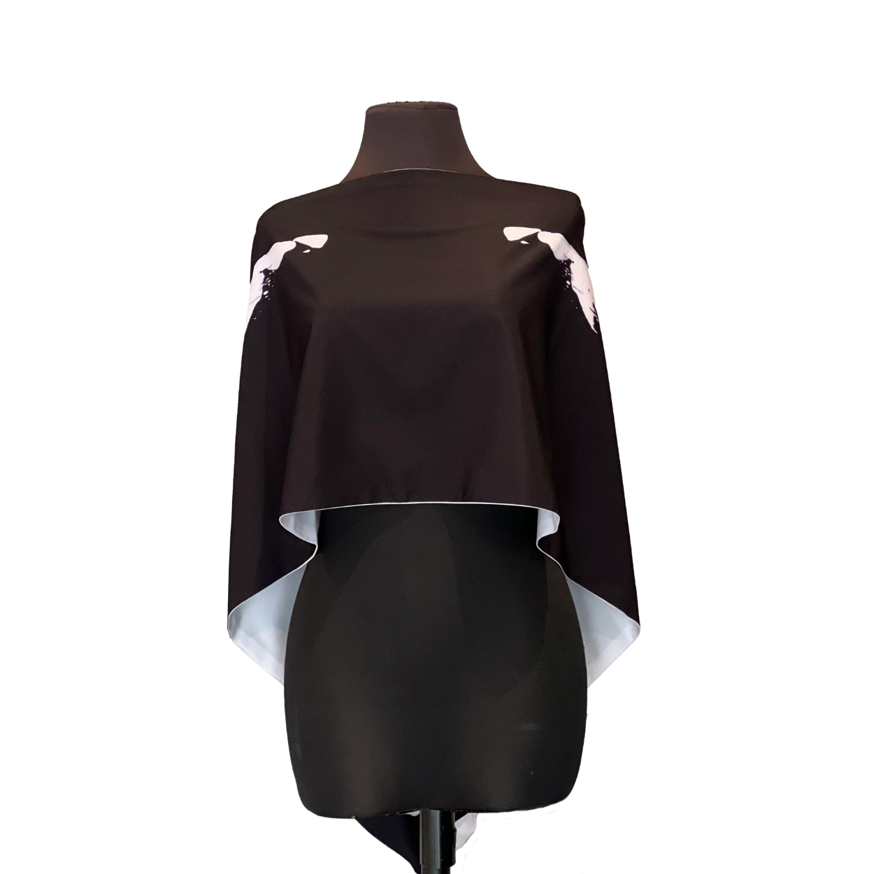 Black and white cape displayed on a dress form, with white accent details on the shoulders.