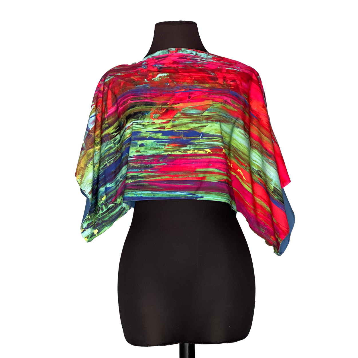 A colorful, abstract-print cape draped on a black mannequin, featuring red, green, and blue hues.