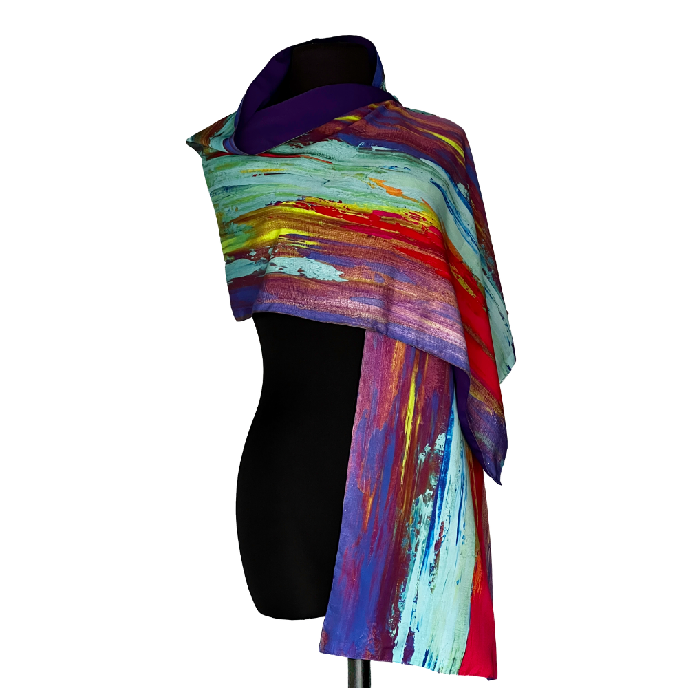 Scarf with abstract brushstroke pattern in blue, red, yellow, and turquoise colors, draped on a black mannequin.