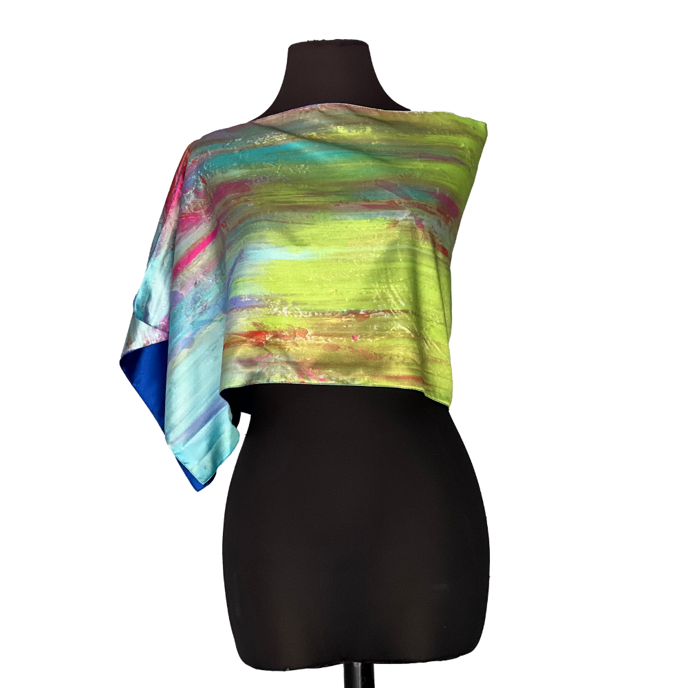 Abstract print silk scarf draped over a black mannequin. Colors include blue, green, and pink.