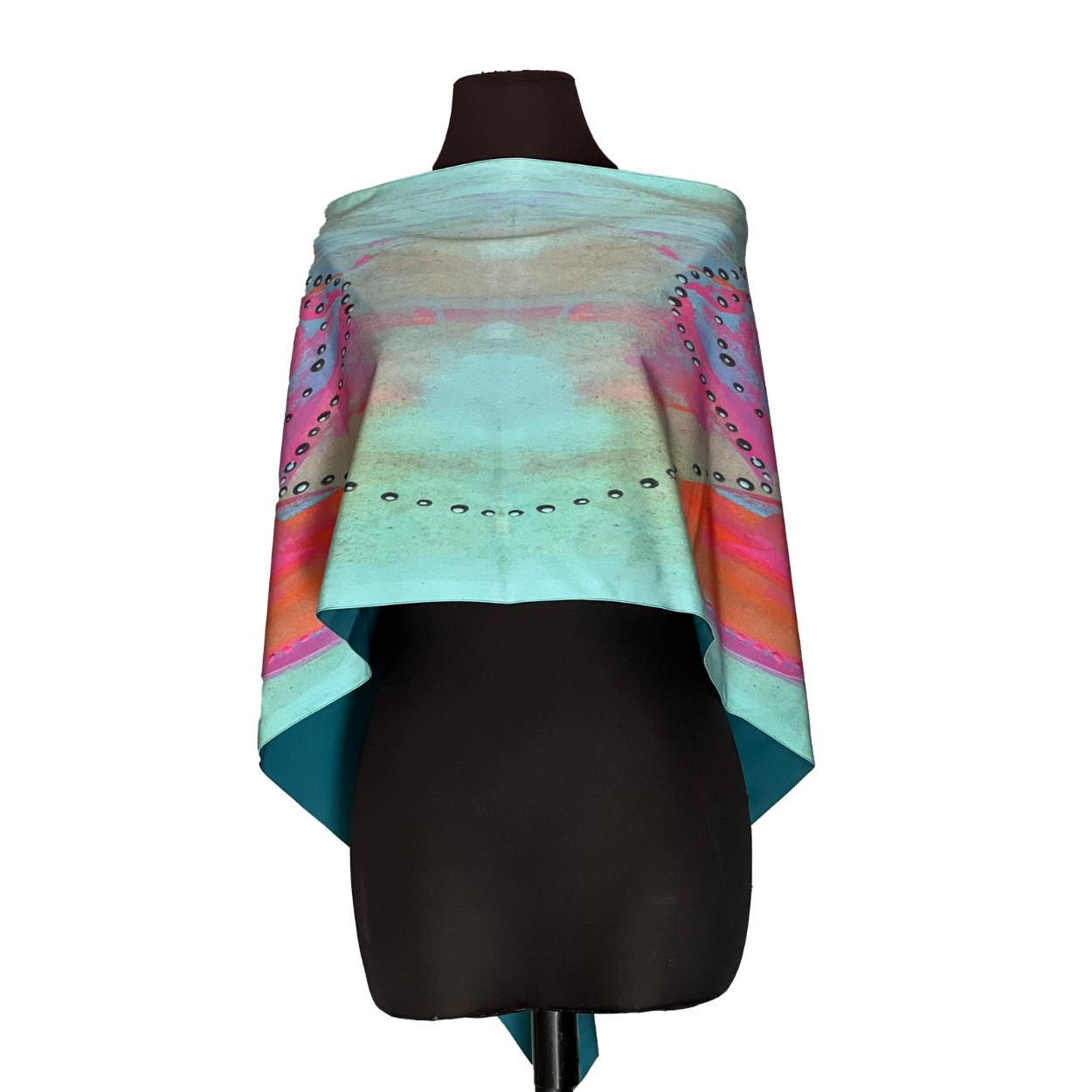 Turquoise, pink, and orange printed shawl draped over a dark mannequin, with small studs along edges.