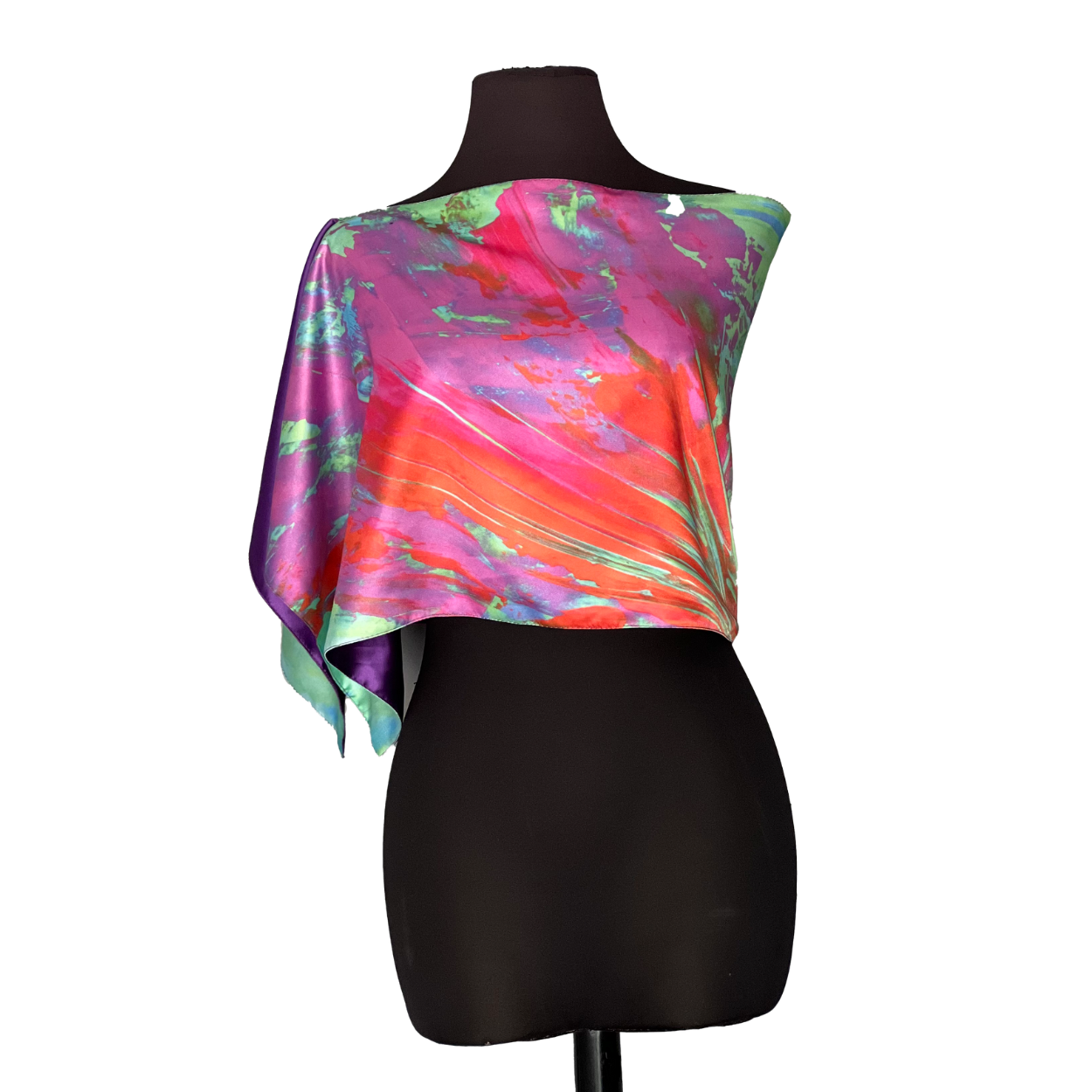 Colorful silk shawl draped on a black mannequin, with shades of pink, orange, and green.