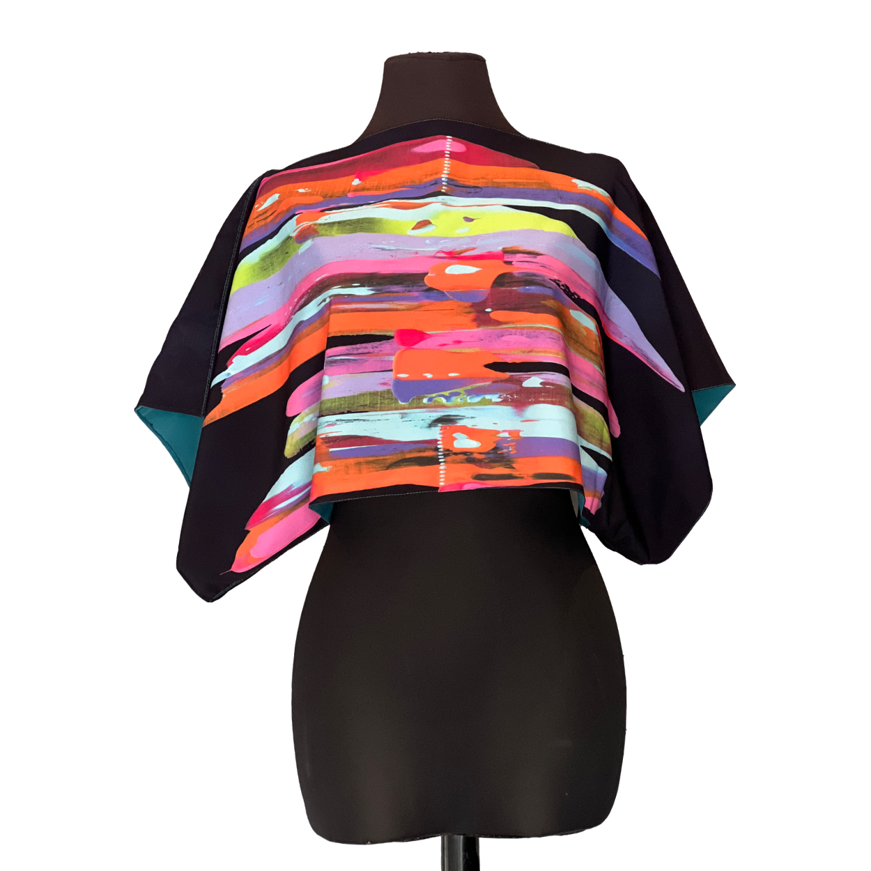 Black torso mannequin wearing a colorful abstract crop top with wide sleeves.