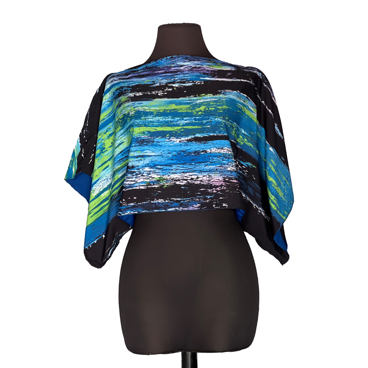 Abstract print blue, green, and black cape-style top on a black mannequin.