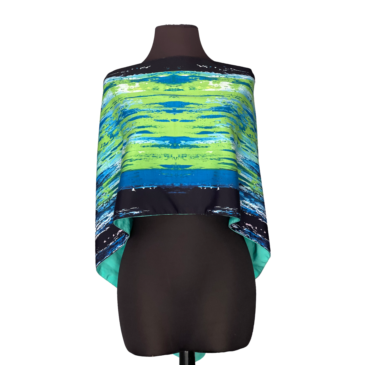 Silk poncho with green, blue, and black abstract pattern on a mannequin.
