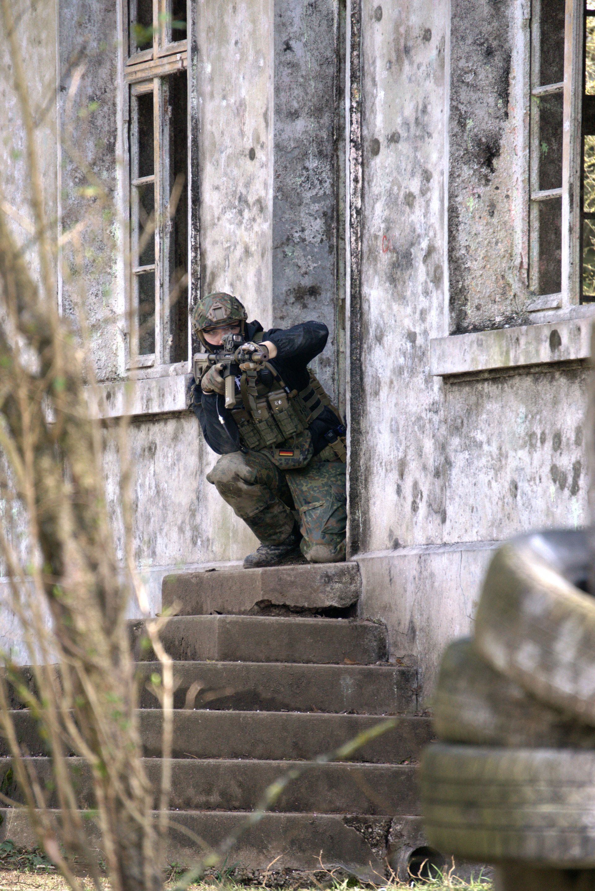 Ein Soldat kniet auf den Stufen eines verlassenen Gebäudes.