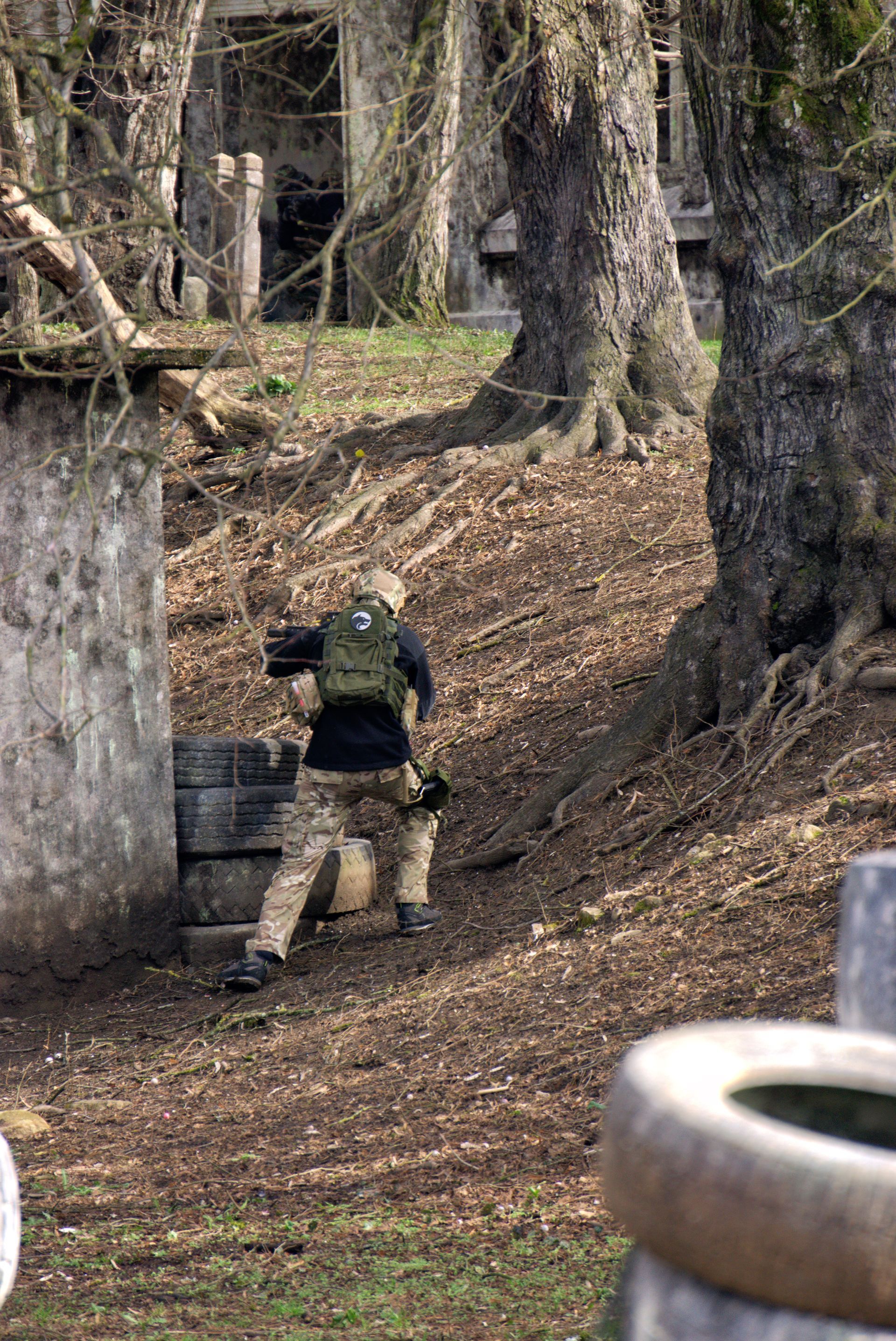 Ein Mann mit einem Rucksack steht neben einem Baum auf einem Feld.