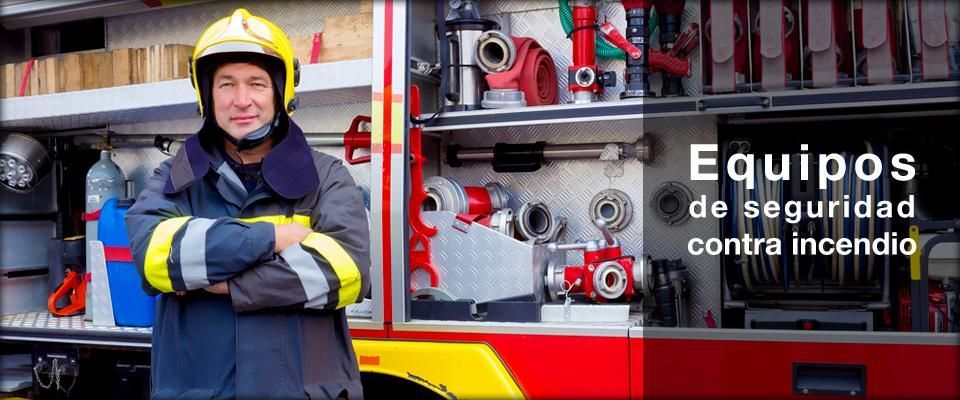 Un bombero está parado frente a un camión de bomberos con los brazos cruzados.
