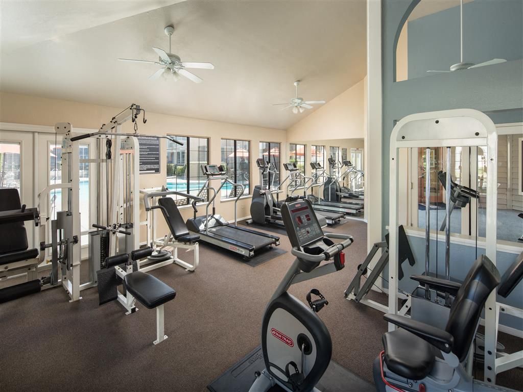 Indoor community gym with treadmills, stationary bikes, and weight machines.