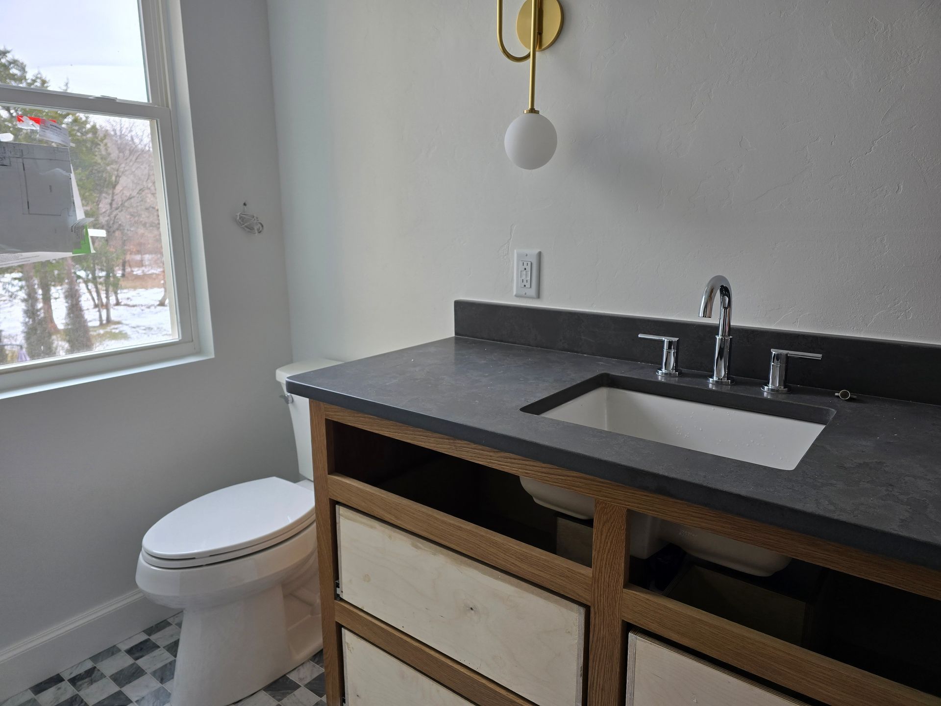 A bathroom with a sink , toilet and window.