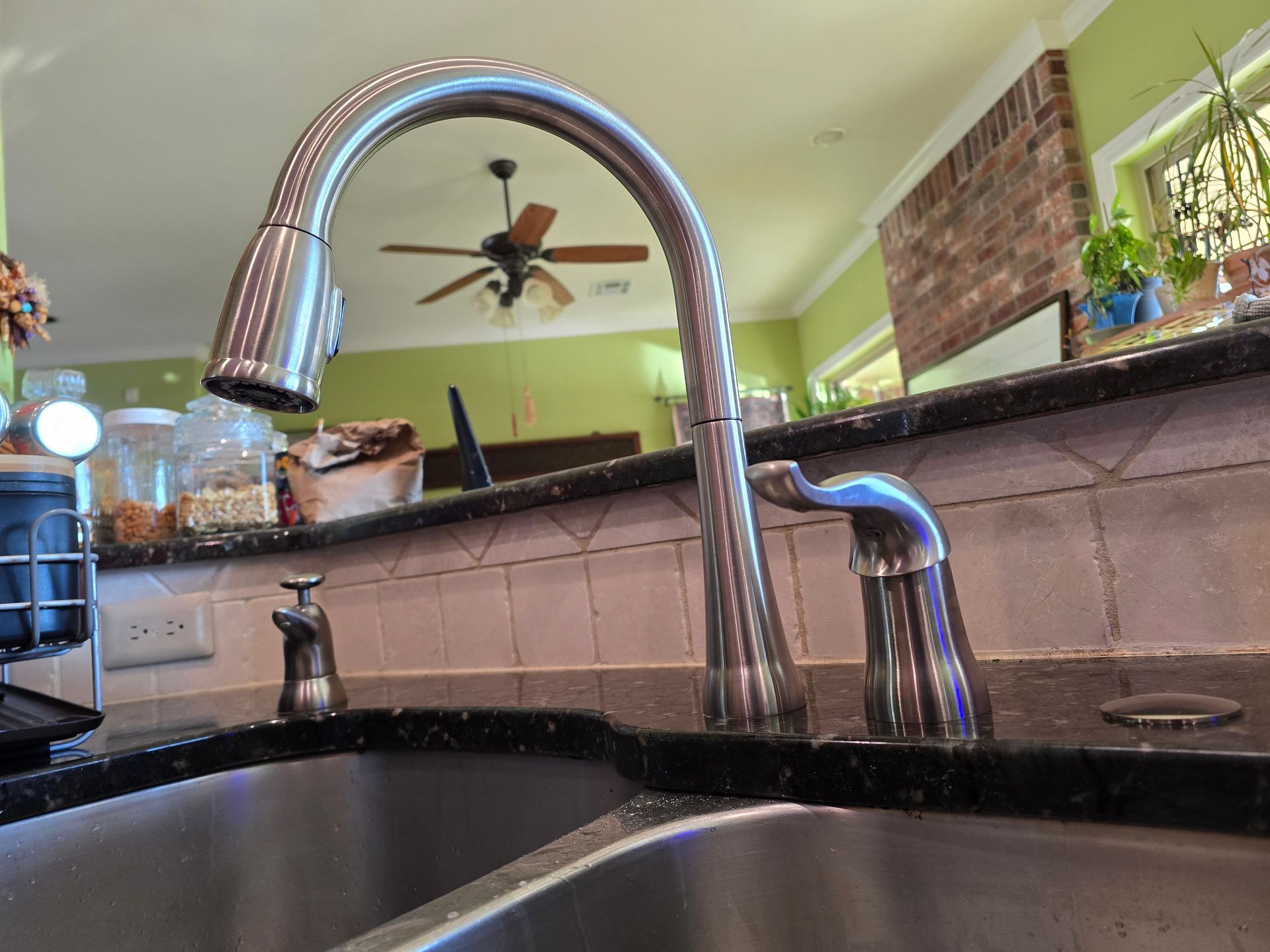 A kitchen sink with a faucet and a ceiling fan