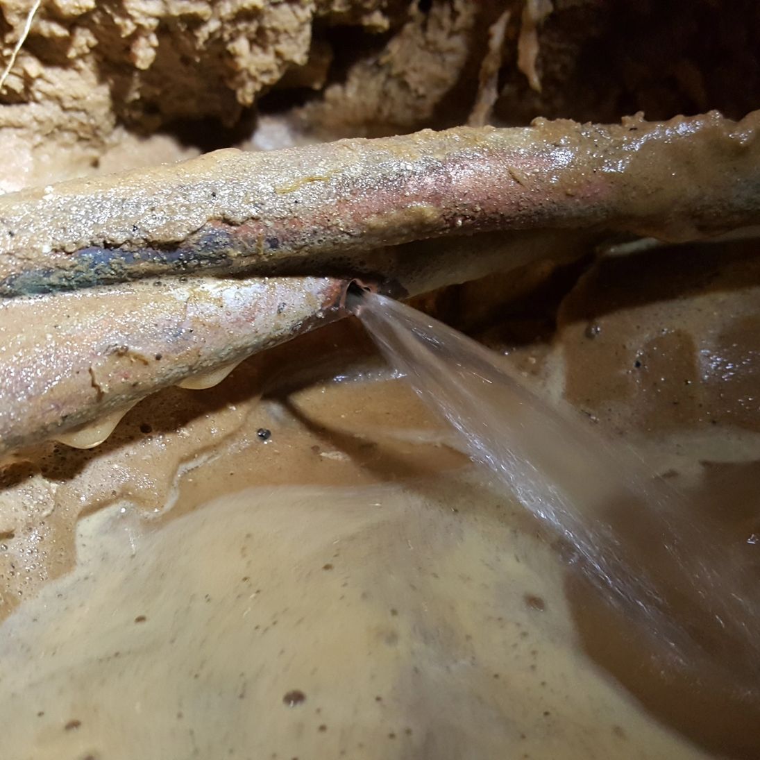 A close up of a copper pipe with a hole in it.