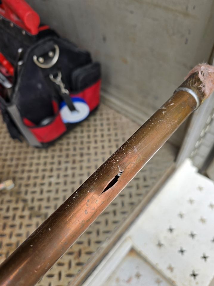 A close up of a copper pipe with a hole in it.