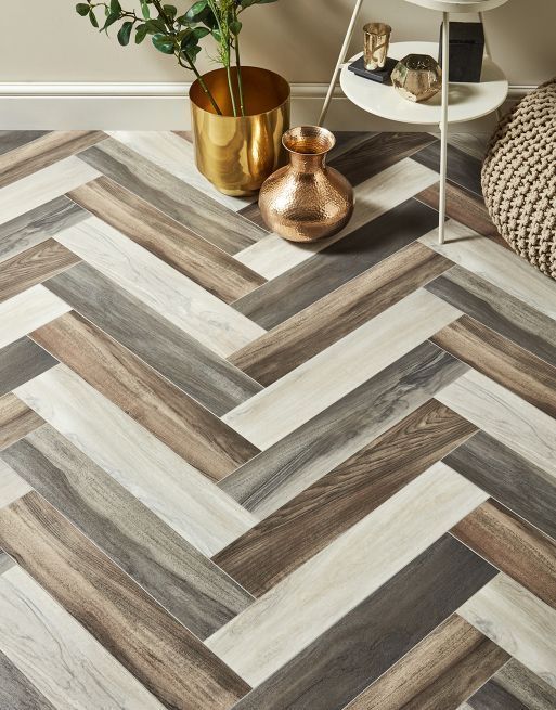 A wooden floor with a herringbone pattern and a vase on it.