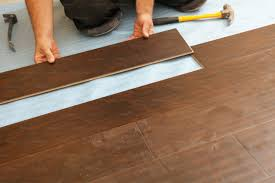 A person is installing a wooden floor with a hammer.