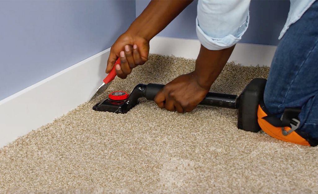 A person is cutting a piece of carpet with a pair of scissors.